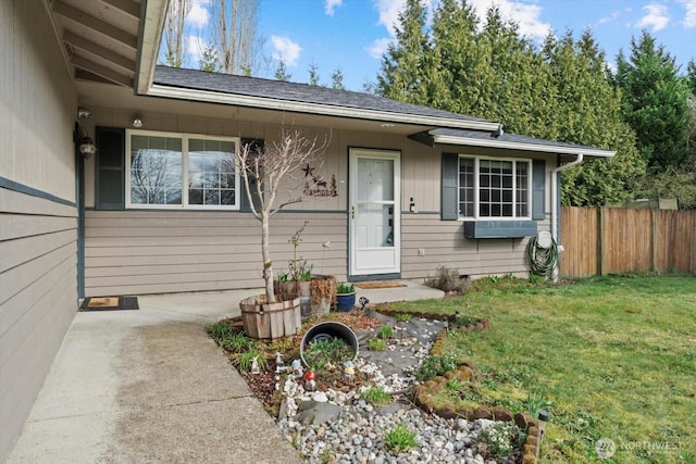 view of front facade with a front yard, fence, roof with shingles, and crawl space