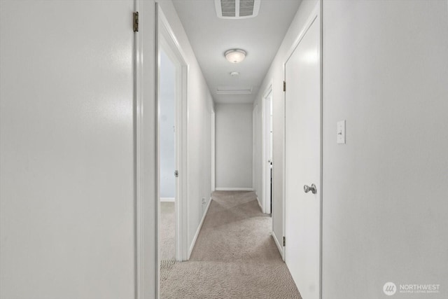 corridor featuring baseboards, visible vents, and light carpet