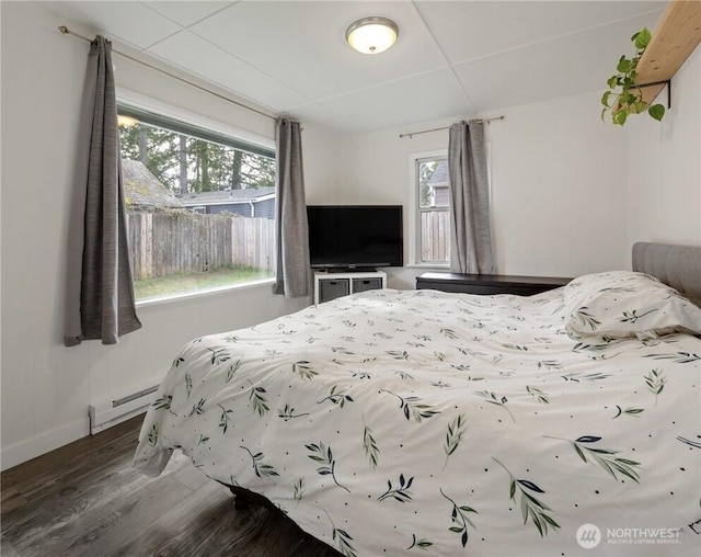 bedroom with wood finished floors, baseboards, and a baseboard radiator