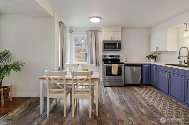 kitchen with a sink, appliances with stainless steel finishes, dark wood-style floors, and white cabinetry