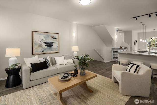 living area with track lighting, dark wood-type flooring, and baseboards