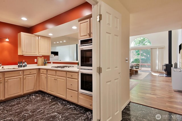 kitchen with a sink, white appliances, marble finish floor, and light brown cabinetry