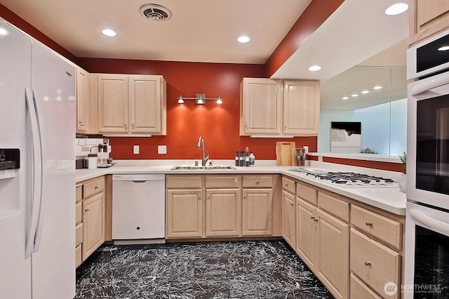 kitchen with visible vents, light brown cabinetry, light countertops, white appliances, and a sink