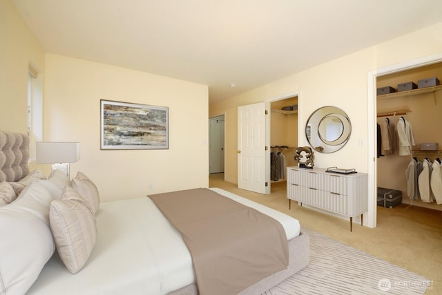 bedroom with a walk in closet and light colored carpet