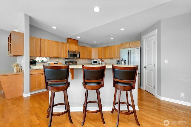 kitchen featuring light wood finished floors, stainless steel appliances, light countertops, and a sink