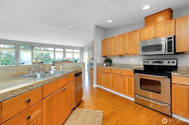 kitchen featuring light wood finished floors, lofted ceiling, recessed lighting, a sink, and appliances with stainless steel finishes