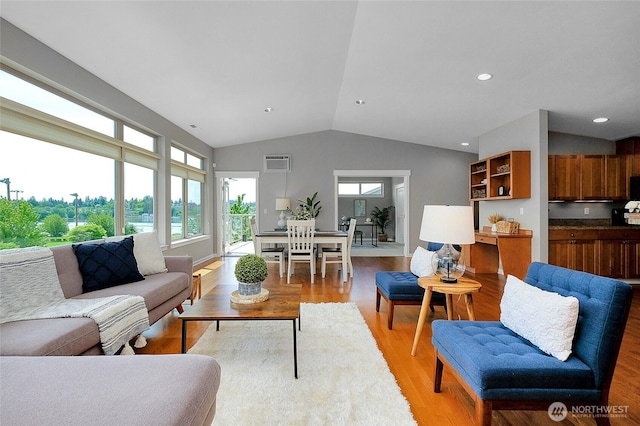 living area with recessed lighting, light wood finished floors, lofted ceiling, and a wall mounted AC