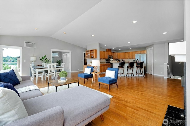 living room with baseboards, lofted ceiling, recessed lighting, an AC wall unit, and light wood-style floors