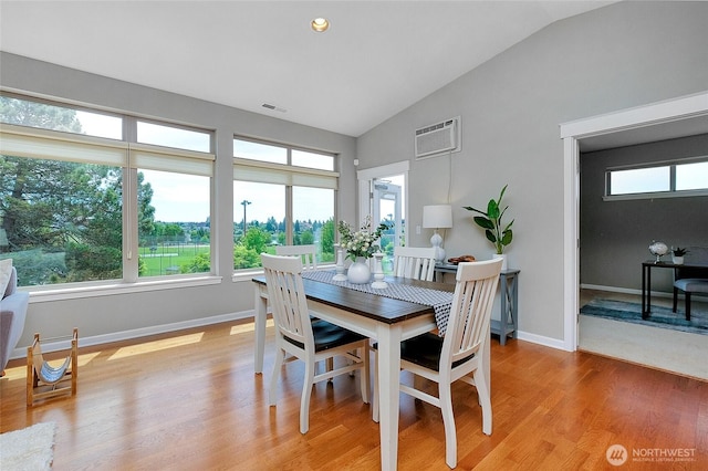 dining area featuring a wall mounted air conditioner, visible vents, a healthy amount of sunlight, and light wood-style flooring