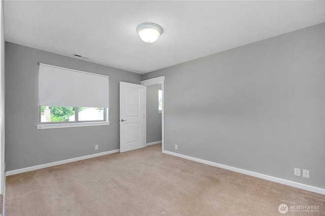 carpeted spare room featuring visible vents and baseboards