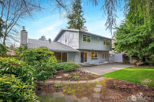 back of house featuring a patio area, a lawn, a chimney, and fence