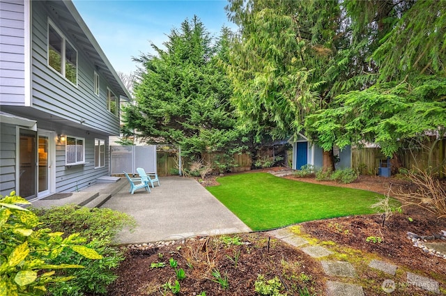 view of yard featuring a patio, a fenced backyard, and an outdoor structure