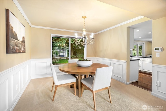 dining room with light colored carpet, a wainscoted wall, and ornamental molding