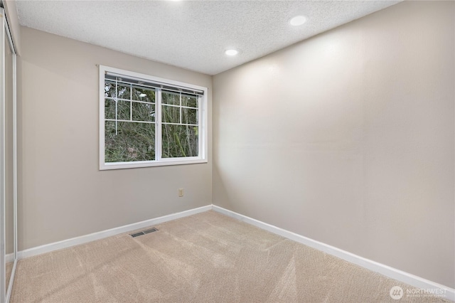 carpeted spare room featuring visible vents, recessed lighting, baseboards, and a textured ceiling