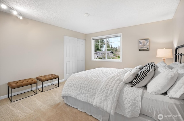 bedroom featuring a closet, baseboards, a textured ceiling, and carpet flooring