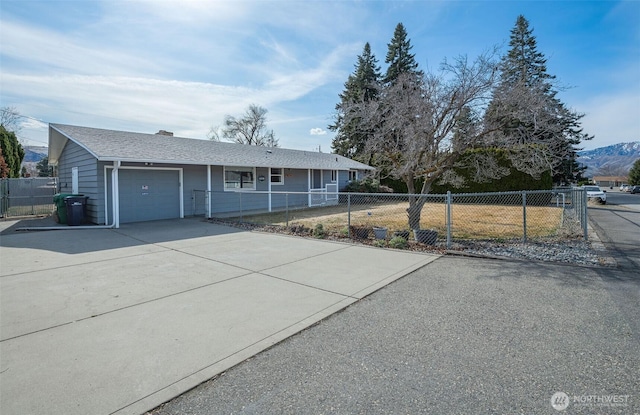 single story home with a fenced front yard, driveway, an attached garage, and a shingled roof