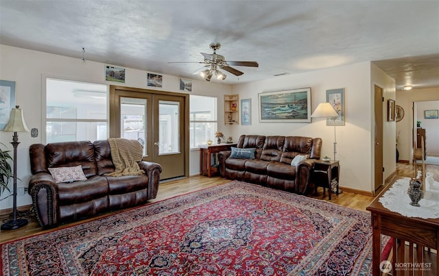 living room with visible vents, baseboards, ceiling fan, light wood-style flooring, and french doors