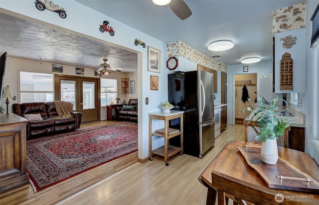 living room with visible vents, baseboards, light wood-style floors, and a ceiling fan