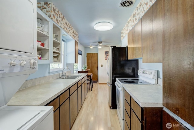 kitchen with visible vents, light countertops, stacked washer and dryer, white electric range oven, and a sink