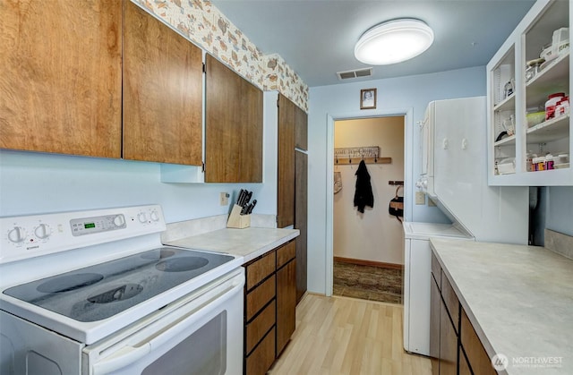 kitchen featuring visible vents, light wood finished floors, light countertops, electric stove, and brown cabinets