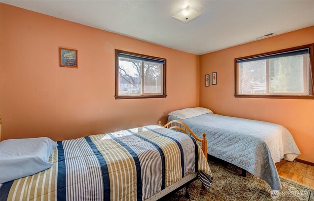 bedroom featuring visible vents, baseboards, and wood finished floors