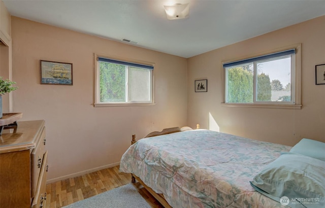 bedroom featuring baseboards, visible vents, and light wood finished floors