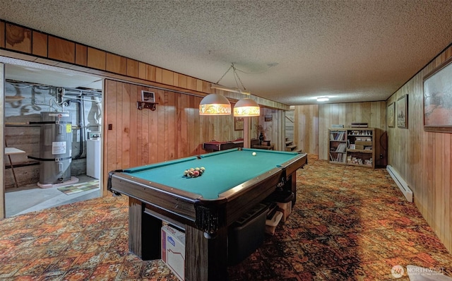 game room with a baseboard radiator, a textured ceiling, secured water heater, and wood walls