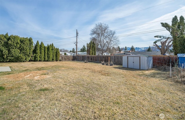 view of yard with a fenced backyard, a storage unit, and an outdoor structure