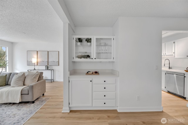 living room featuring baseboards, light wood finished floors, and a textured ceiling