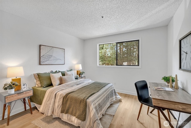 bedroom with a textured ceiling, baseboards, and wood finished floors