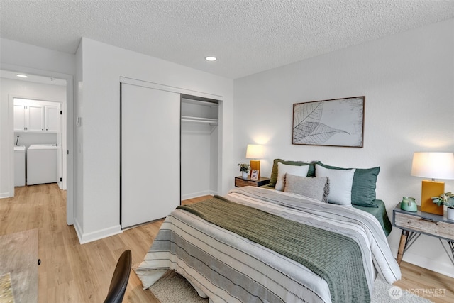 bedroom with a textured ceiling, light wood-type flooring, a closet, and washing machine and clothes dryer