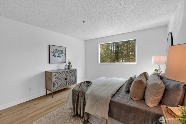 bedroom with baseboards, a textured ceiling, and wood finished floors