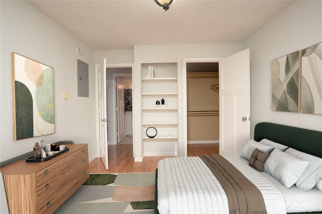 bedroom featuring electric panel, a textured ceiling, wood finished floors, a closet, and baseboards