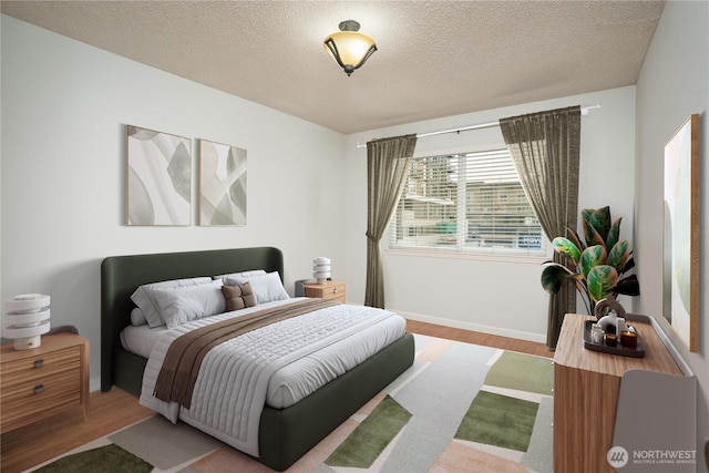 bedroom featuring baseboards, a textured ceiling, and wood finished floors