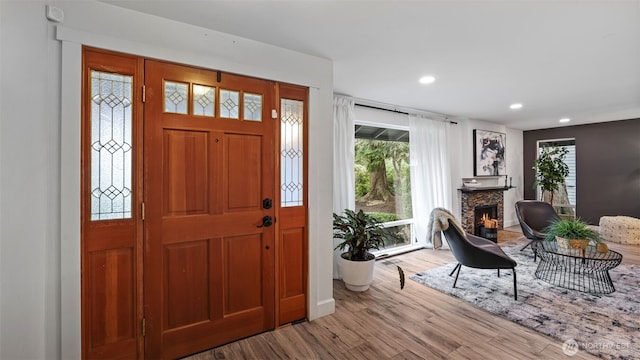 foyer entrance with a fireplace, recessed lighting, wood finished floors, and baseboards