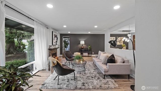 living room featuring recessed lighting, a stone fireplace, light wood-style flooring, and baseboards