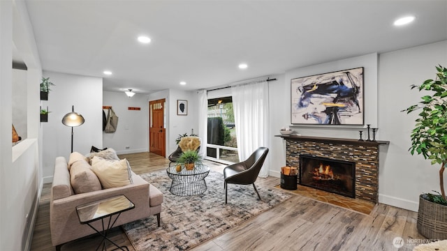 living room featuring a tiled fireplace, recessed lighting, baseboards, and wood finished floors