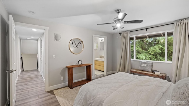 bedroom with a ceiling fan, baseboards, light wood finished floors, and connected bathroom