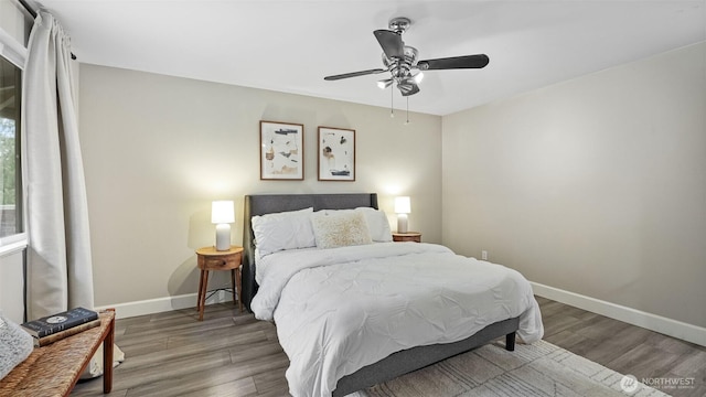 bedroom with a ceiling fan, baseboards, and wood finished floors