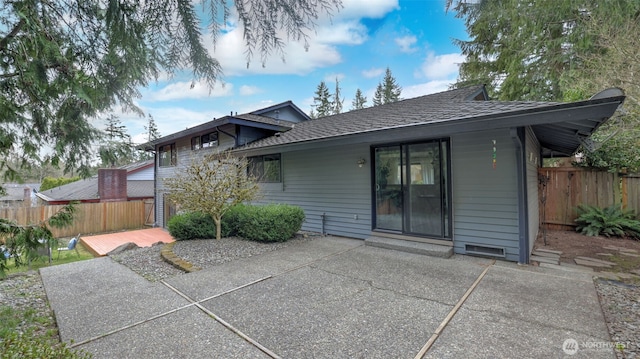 rear view of property featuring a patio area, roof with shingles, and fence