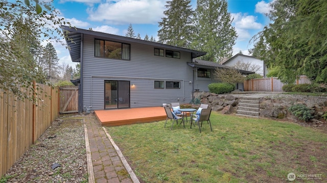 rear view of house with a lawn, a deck, and fence