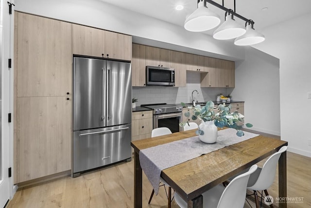 kitchen featuring light wood finished floors, light brown cabinets, stainless steel appliances, and tasteful backsplash