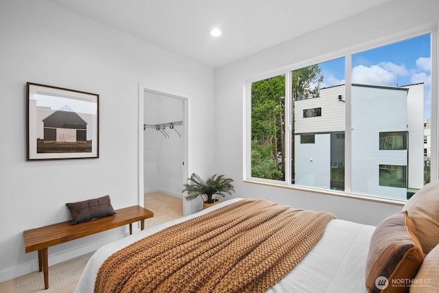 carpeted bedroom featuring a walk in closet, recessed lighting, baseboards, and a closet