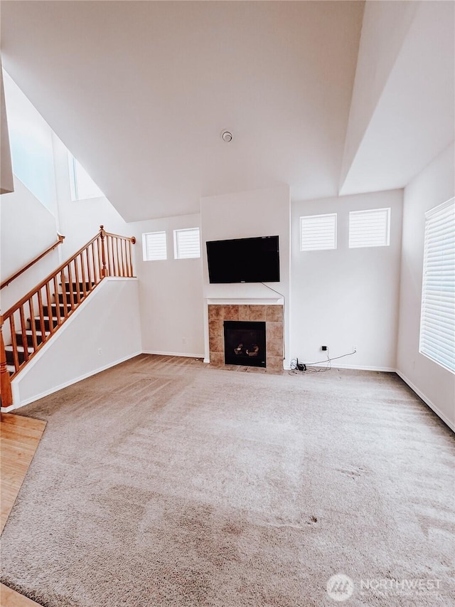 unfurnished living room with baseboards, carpet, a fireplace, and stairs