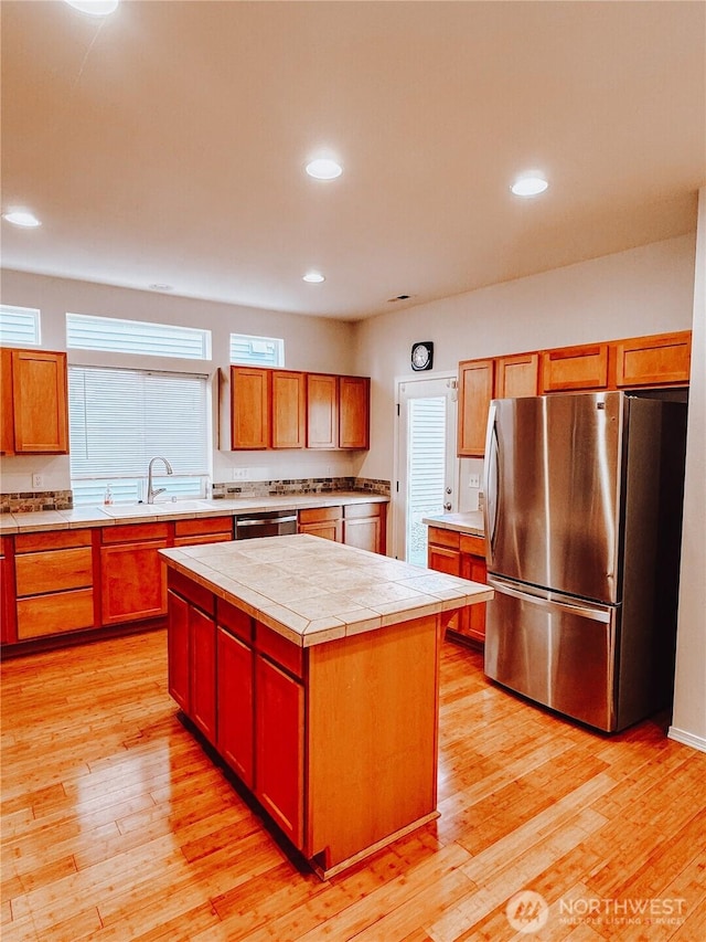 kitchen with a sink, light wood-style flooring, a kitchen island, and stainless steel appliances