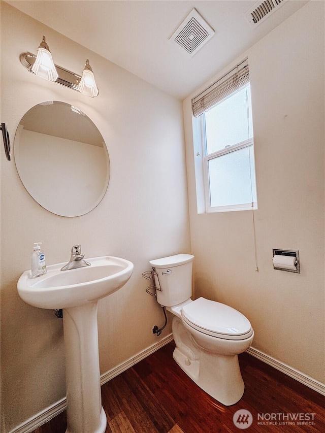 half bathroom featuring visible vents, baseboards, toilet, and wood finished floors