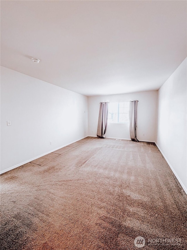 unfurnished room with light colored carpet and baseboards