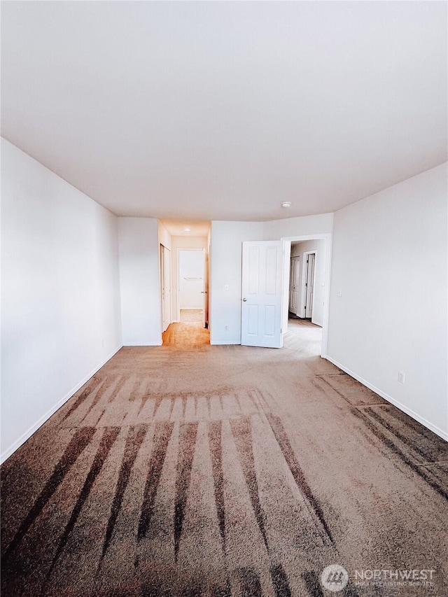 spare room featuring light carpet and baseboards