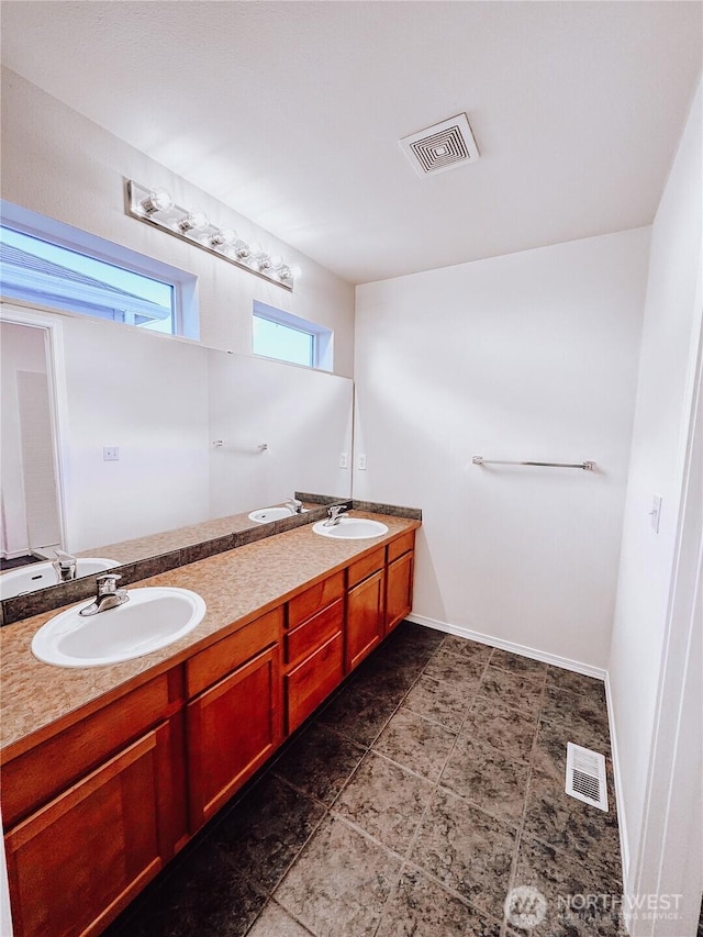 full bath with double vanity, visible vents, baseboards, and a sink