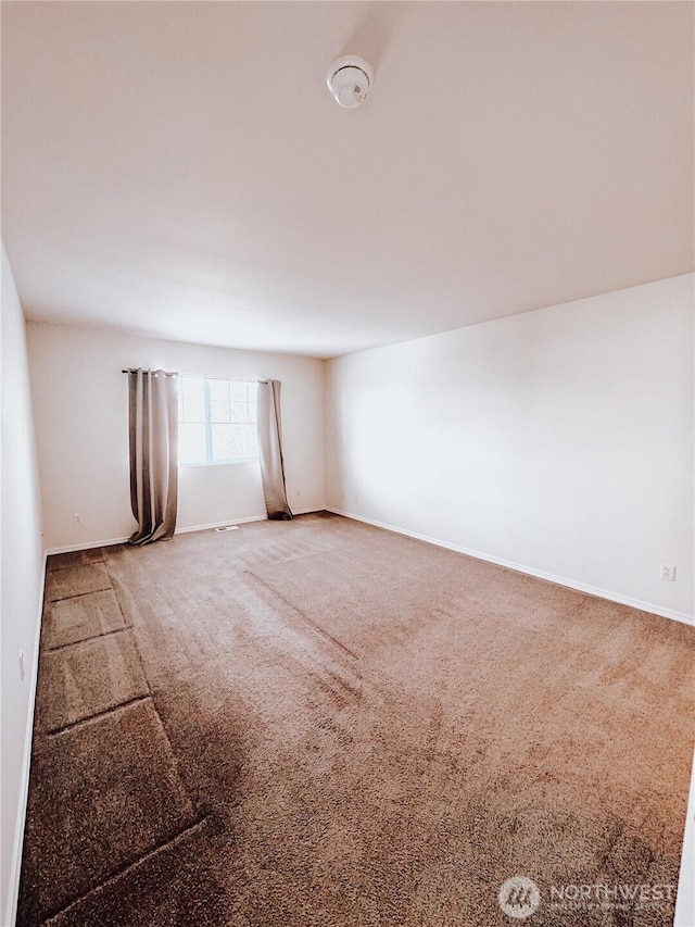 unfurnished room with carpet flooring and baseboards